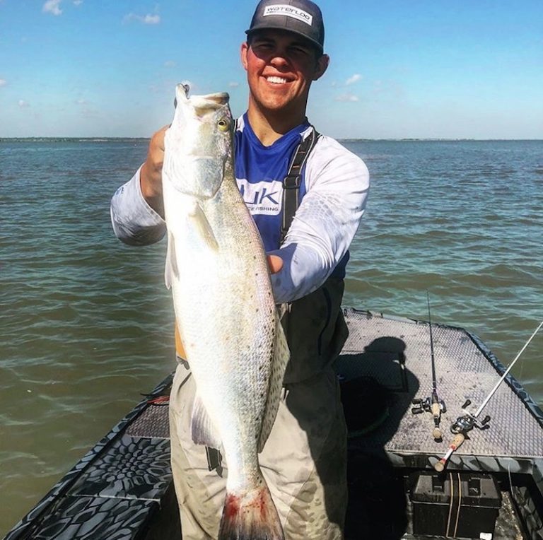 Angler holding a speckled trout on an Uncle J boat