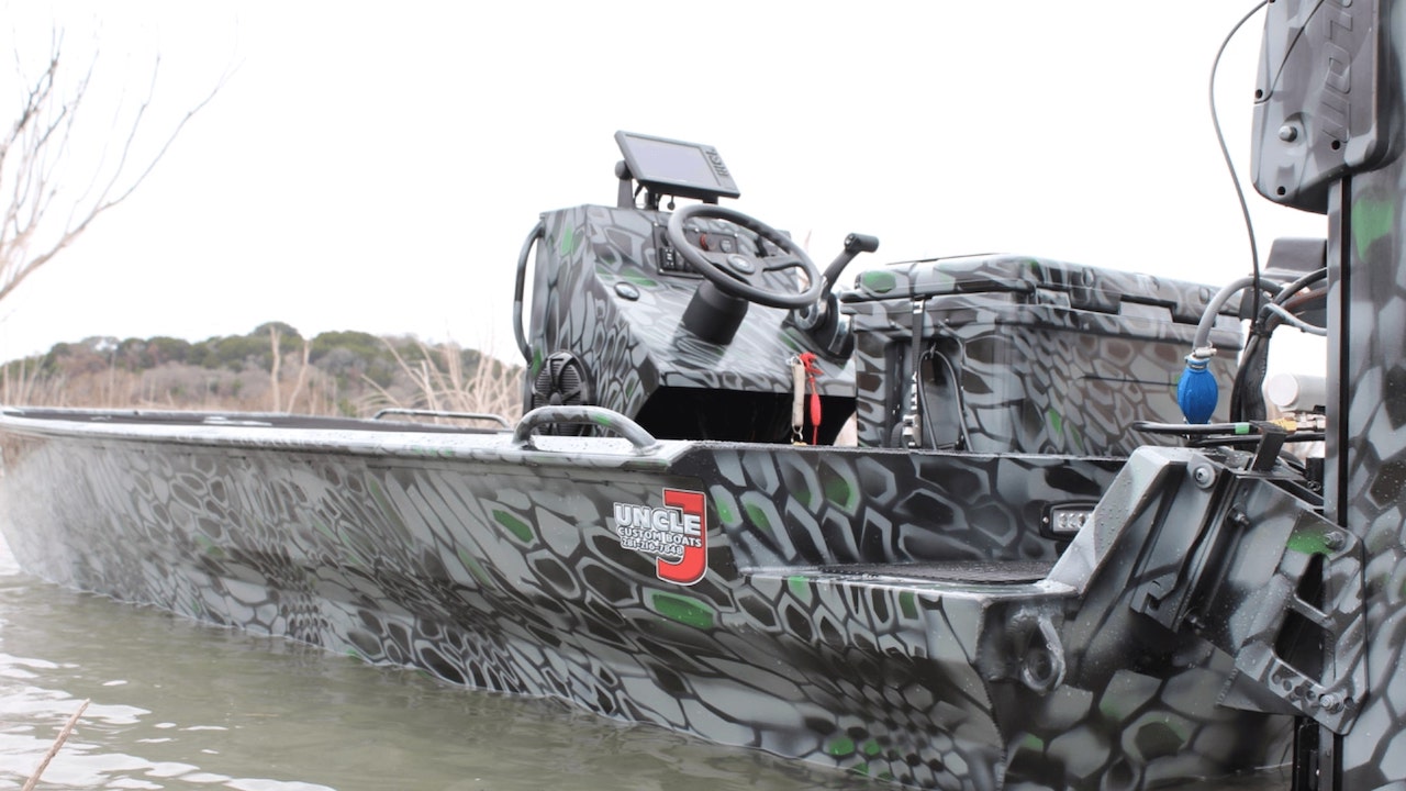 Gray and green snakeskin camo Uncle J boat with a center console on the water