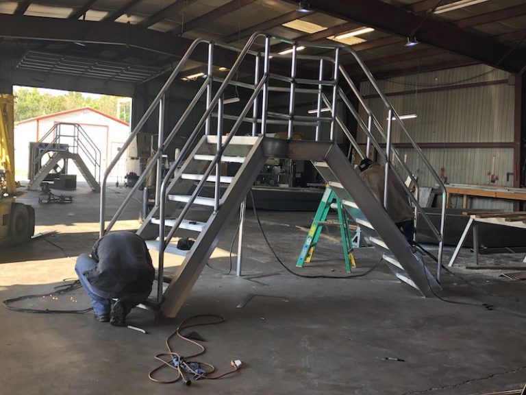 Welder working on a set of aluminum crossover stairs in the shop