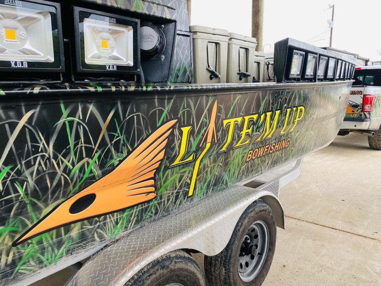 Side of the Lite'm Up Bowfishing boat with its grass camo wrap and floodlights