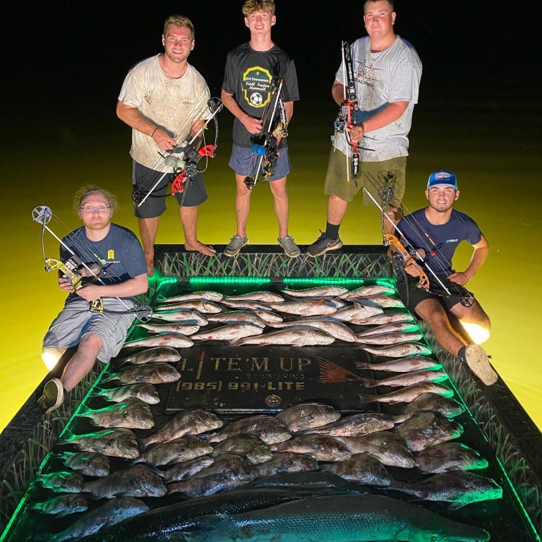 Five bowfishermen with a deck full of fish on the Lite'm Up boat at night