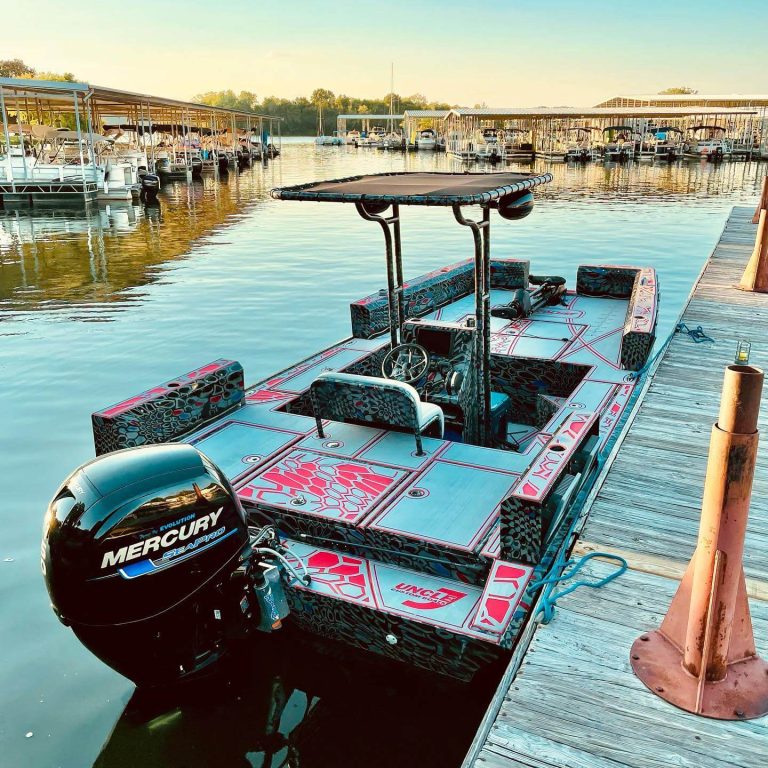 Gray and red camo Uncle J boat with a Mercury outboard at a marina dock