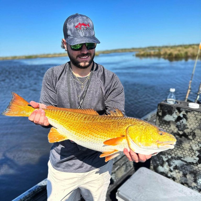 Angler holding a redfish on an Uncle J boat in the marsh