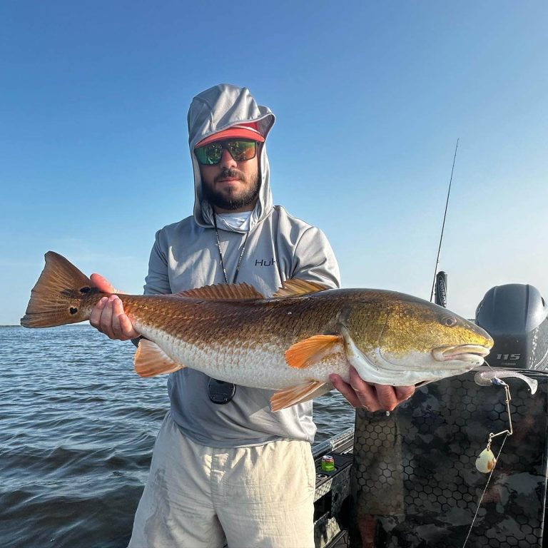 Angler holding a redfish on an Uncle J boat with an outboard motor