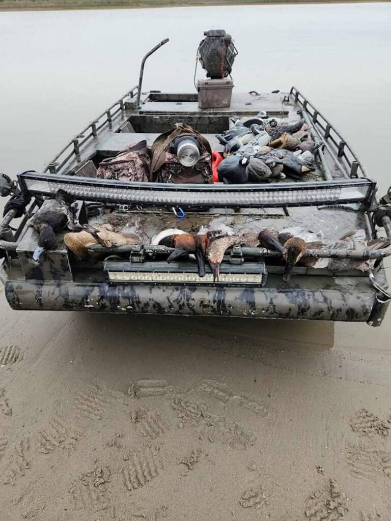 SoTex Outdoors duck boat with a bow light bar and a load of ducks and decoys, beached on sand