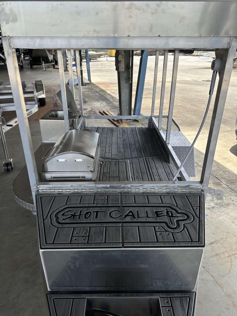 Aluminum cooking trailer with a built-in grill and a Shot Caller logo on the front panel