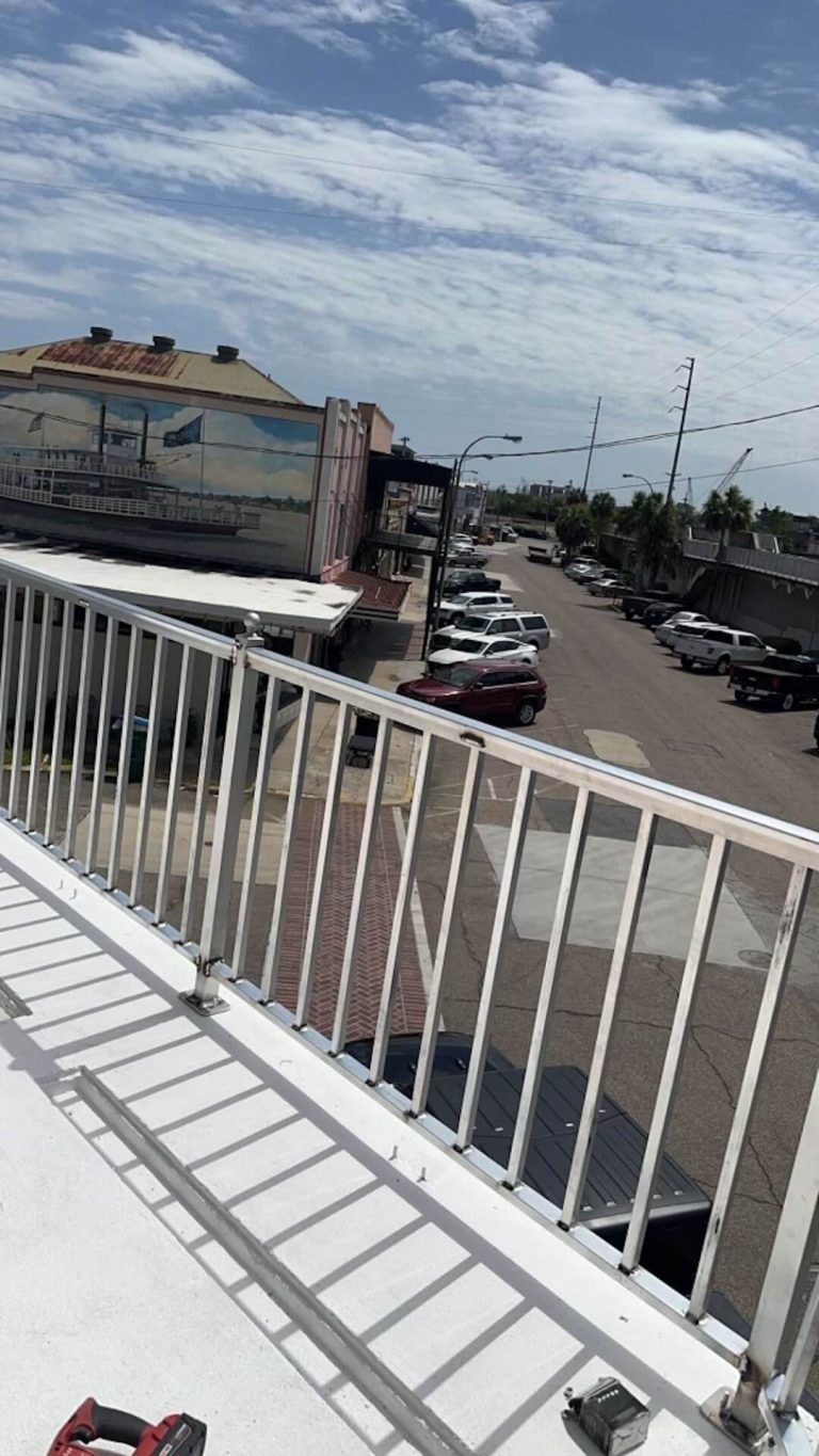 Aluminum railing along a rooftop walkway above a parking lot