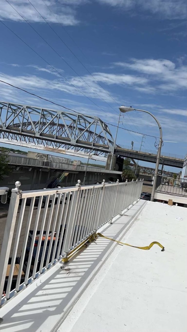 Aluminum railing along a walkway beside a steel bridge