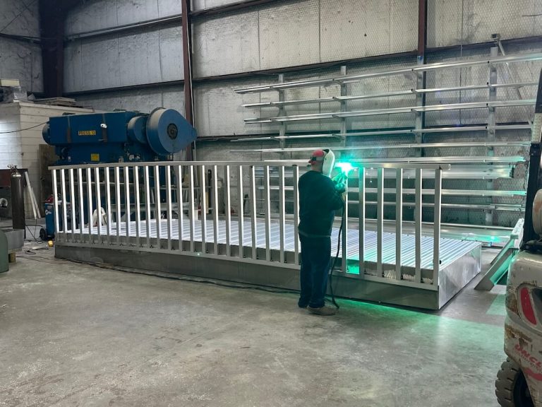 Welder building an aluminum walking bridge with railings in the shop