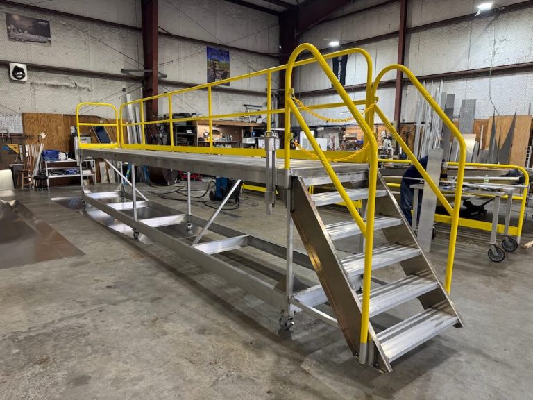 Long aluminum work platform with stairs and yellow handrails