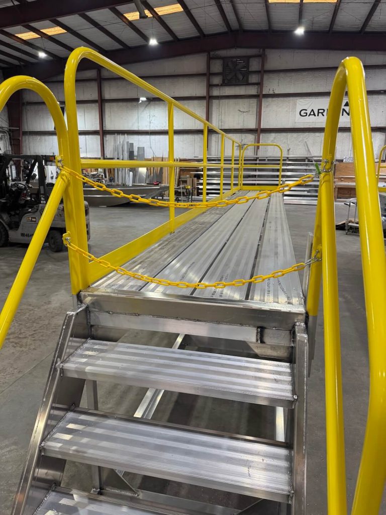 Walkway of an aluminum work platform with yellow handrails