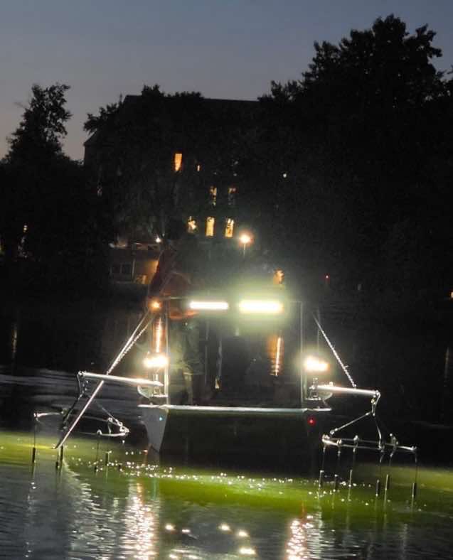 Uncle J electro-fishing boat at night with work lights and booms deployed